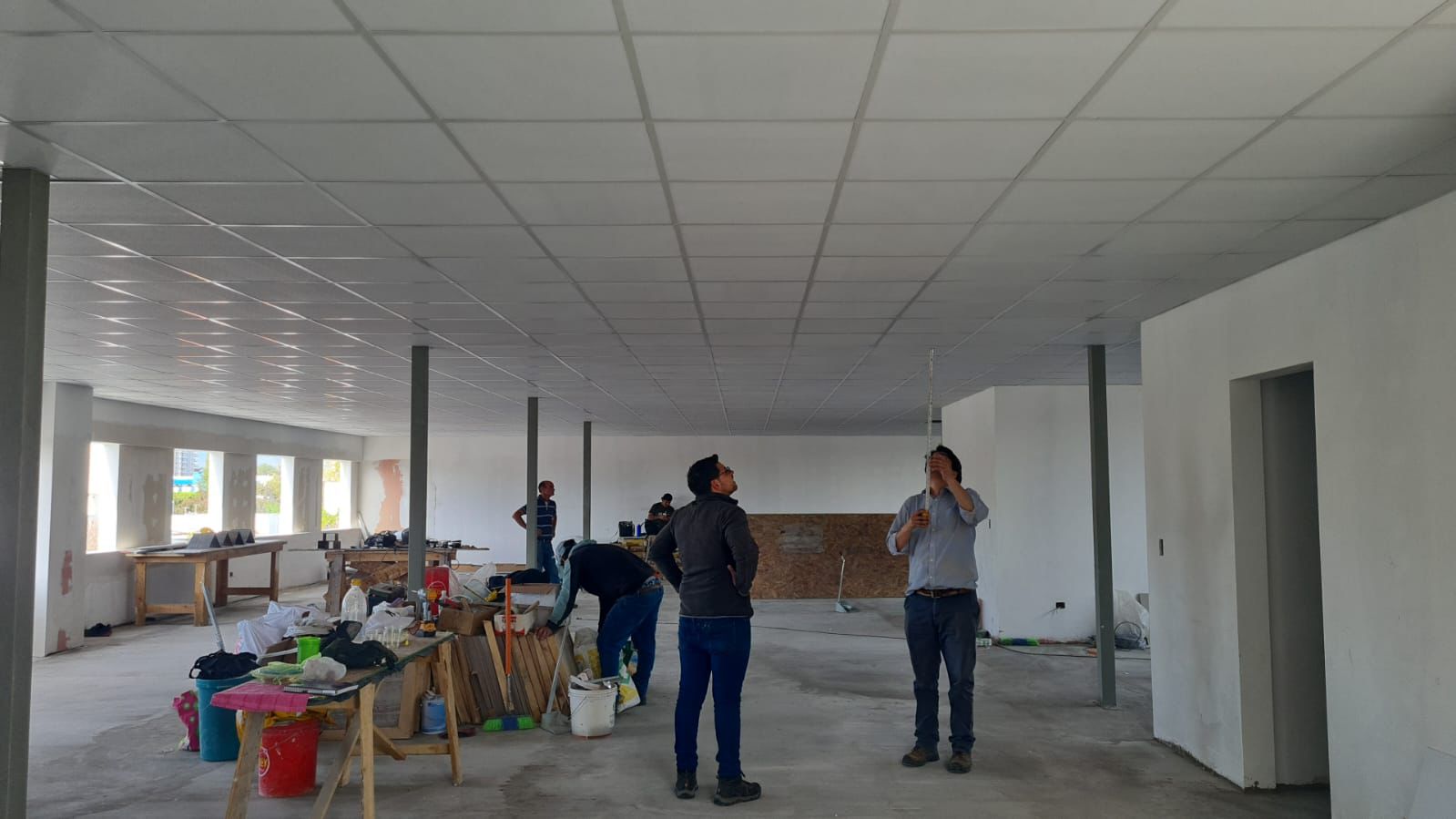 Salón amplio en obra con cielo modular montado entre pilares