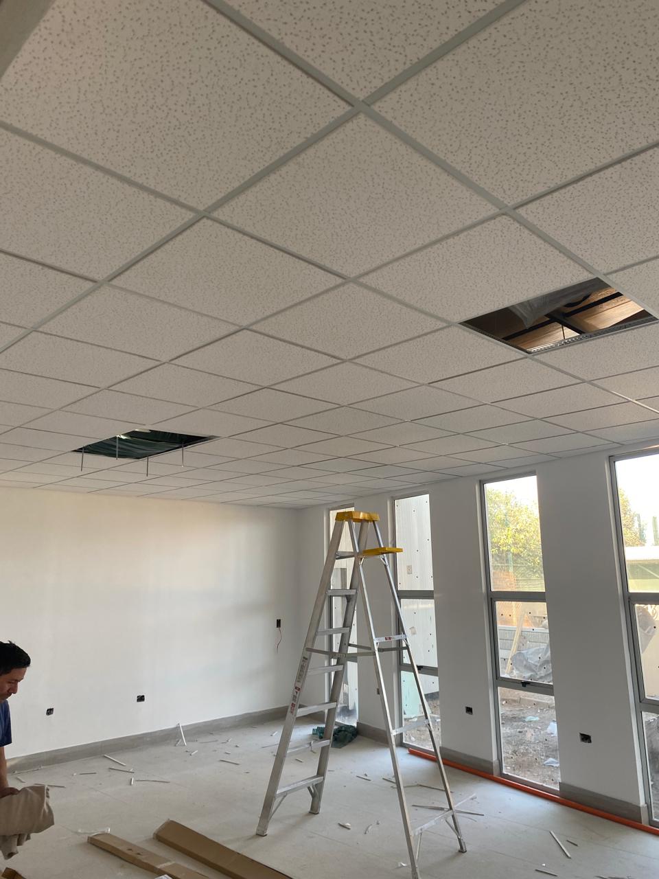Sala en obra con escalera y cielo modular en montaje