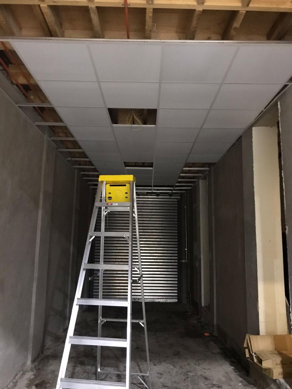 Pasillo en obra con escalera y cielo modular en montaje